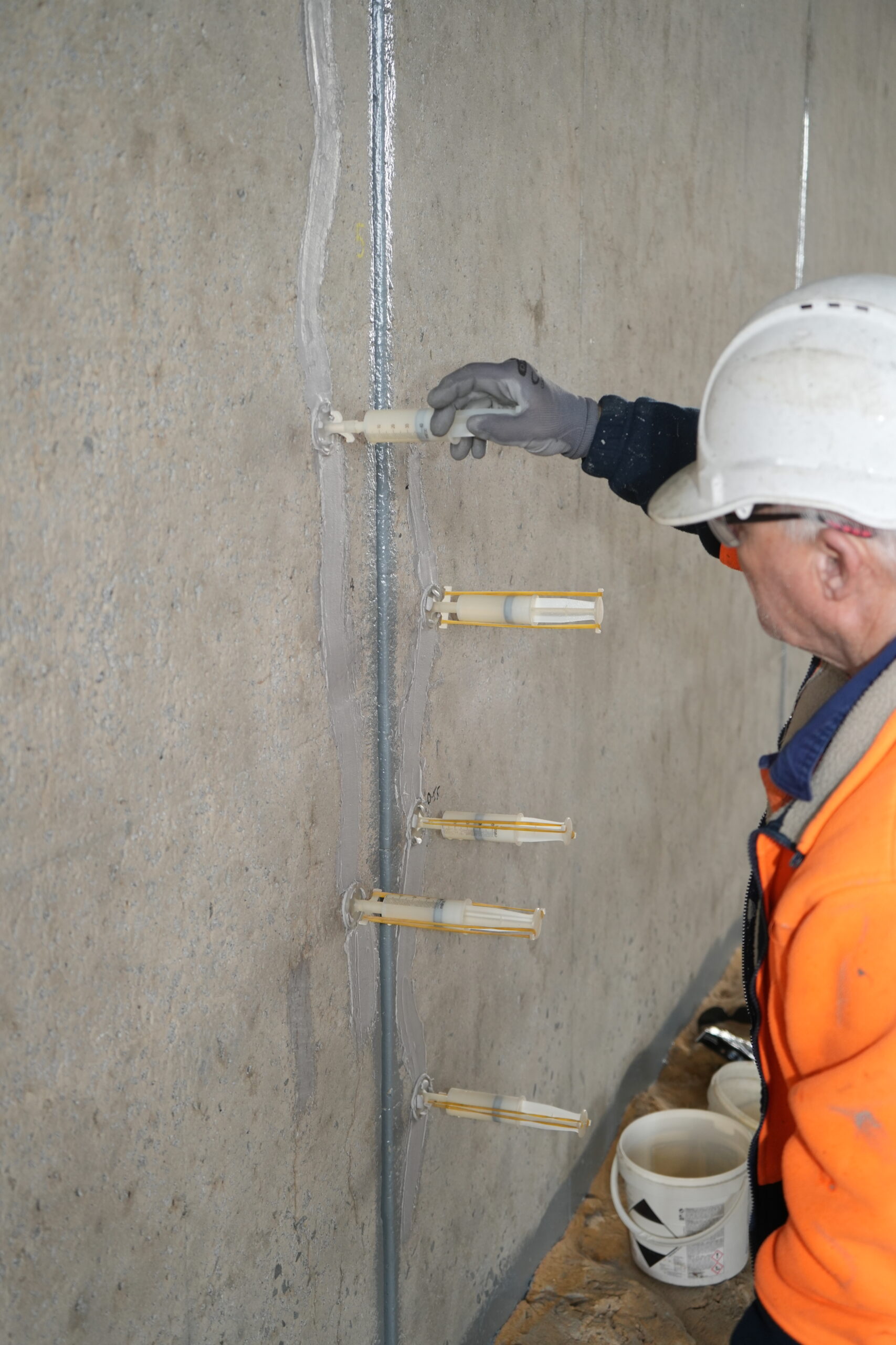 High-pressure chemical injection resin being pumped into structural concrete cracks